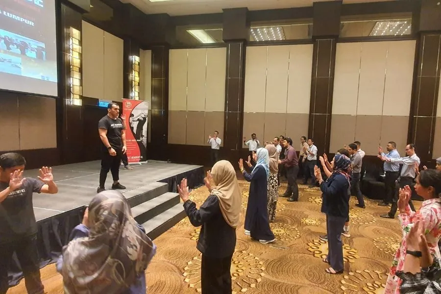 A Jeet Academy KL instructor leading a large corporate self-defence workshop in a hotel ballroom