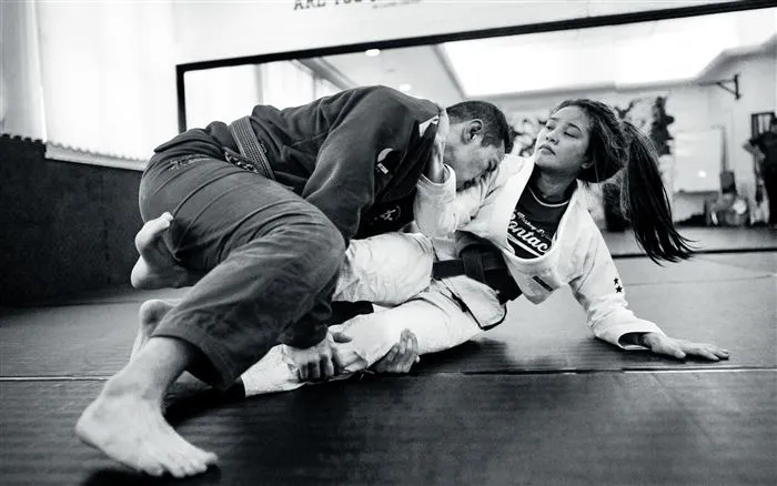 Two adults grappling on the mat during a Brazilian Jiu-Jitsu class