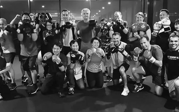 A group boxing class posing with gloves on after a session