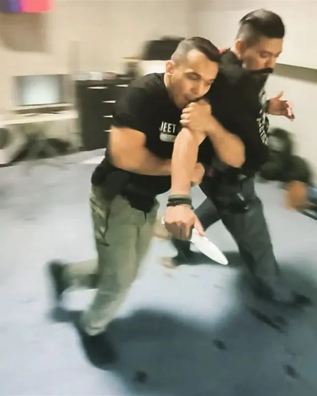 Two Jeet Academy KL instructors in a close-quarters knife defence drill, motion-blurred
