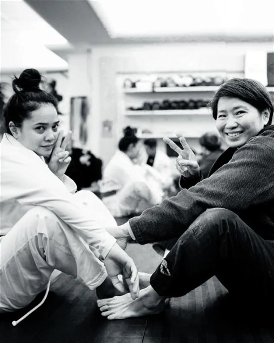 Two members smiling together on the mat after a class
