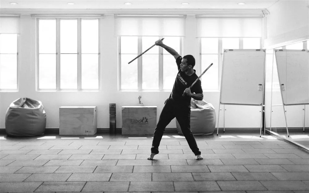 Instructor practicing double-stick Kali (Filipino Martial Arts) footwork and strikes at the studio