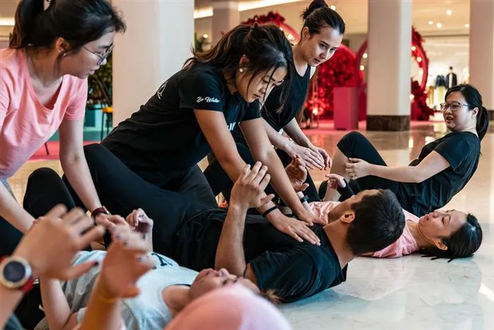Participants practising a ground-defence drill at a mall atrium workshop