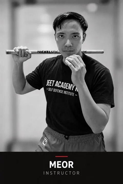 Black-and-white portrait of Meor Zuhairy, Filipino Martial Arts instructor at JEET Academy KL, holding rattan Kali sticks