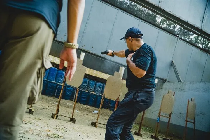 An instructor firing at silhouette targets on a firearms range